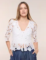 Bolero corto de encaje blanco con motivo floral y transparencias, escote en V pronunciado y mangas tres cuartos.