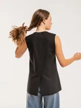 Chaleco color crema de lino con corte sastrero, largo a la cadera, forro interno, botones delanteros, silueta levemente entallada y tajo cruzado en la espalda.