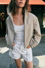Cazadora con capucha ajustable, manga larga con puños elásticos, bolsillos delanteros y bajo ajustable con cordones. Cierre frontal con cremallera y diseño estampado a cuadros.