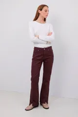Pantalón tipo jean de corte recto y tiro medio, color burdeos, con costuras a tono y abertura lateral en el ruedo.