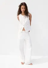 Jeans blancos de silueta balloon, tiro regular y largo standard, con detalles bordados sutiles en las perneras.