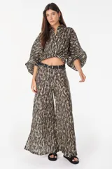 Pantalón de lino italiano con diseño estampado a rayas verticales en tonos negro y beige, de tiro medio y corte ancho.