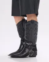 Bota texana de cuero negro con bordados en el caño, punta fina y correa con hebilla metálica.