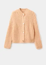 Cardigan de punto grueso color beige, de cuello redondo, manga larga y diseño recto. Presenta cierre frontal con botones efecto joya.