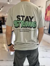 Remera gris de manga corta con estampa frontal y en la espalda con la frase "Stay Strong" y texto descriptivo de la marca Duxon Originals.