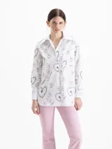 Camisa de poplin blanca con rayas verticales y estampado de corazones formados por cadenas, corte holgado, cuello clásico, mangas largas y bolsillo aplicado en el frente.