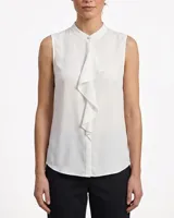 Camisa sin mangas de color blanco, con cuello mao, cierre frontal con botones ocultos y detalle de volados en la parte delantera.