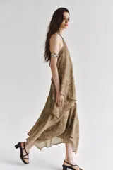 Top de cuello halter con tiras cruzadas para atar al cuello, hombros descubiertos y bajo asimétrico con caída drapeada y textura rústica con estampado sutil.