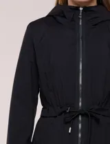Campera liviana negra de silueta semilarga, con capucha fija, cuello alto, cierre frontal y cordón ajustable en la cintura.