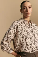 Camisa de manga larga con diseño de rayas verticales en tonos grises y blancos, cuello camisero y cierre frontal con botones.