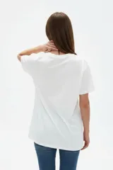 Remera de algodón color beige con estampado frontal de un corazón rosado que contiene un moño. Tiene cuello redondo y mangas cortas.