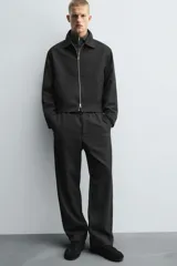 Pantalón regular fit color marrón oscuro, confeccionado en tejido con viscosa. Cuenta con cintura elástica, bolsillos delanteros y detalle de bolsillos traseros de vivo. El cierre frontal es con cremallera y botón.