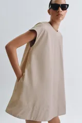 Vestido corto Zara de la colección ZW Collection, color beige, confeccionado en mezcla de algodón. Presenta cuello redondo, manga corta, bolsillos laterales ocultos en costura, bajo evasé y cierre en la espalda con cremallera.