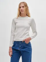 Camiseta blanca de manga larga, con cuello redondo y tejido acanalado. Tiene un corte tipo crop y calce ajustado al cuerpo.