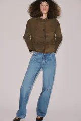 Jeans de tiro medio con corte bootcut, confeccionados en denim azul con efecto lavado y ligeros desgastes. Presentan diseño de cinco bolsillos, trabillas en la cintura y cierre frontal con cremallera y botón.