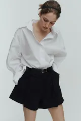 Short negro de tiro alto con pliegues tableados, bolsillos al bies y corte holgado.