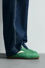 Zapatilla de cordones de estilo retro, con parte superior de serraje color bordó y detalles en piel lisa color rojo. Suela ultrafina de goma en tono marrón oscuro.