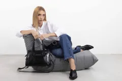 Cartera mini tote de cuero negro con acabado charol, diseño estructurado, doble asa corta de mano y correa larga ajustable y desmontable. Cuenta con cierre principal y placa metálica con la marca grabada en el frente.