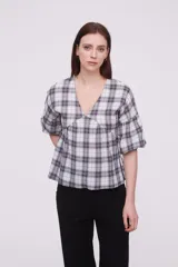Blusa de algodón con estampado a cuadros, cuello en V, corte holgado y mangas cortas abullonadas con frunces.