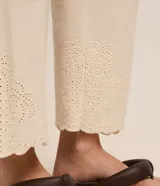 Pantalón recto de cintura alta, color beige, confeccionado en viscolino con detalle de textura perforada con diseño de palmeras en el bajo. Cuenta con elástico en la parte posterior de la cintura y cierre frontal tradicional.