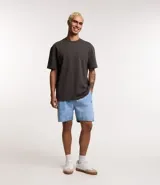 Bermuda de jean azul claro, con cintura elástica y cordón de ajuste. Presenta bolsillos laterales y un tag aplicado en la parte trasera.