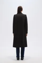 Tapado largo cruzado de poliéster, color negro con finas rayas verticales blancas (pinstripe). Presenta solapas anchas de muesca y doble botonadura.