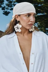 Camisa de lino color blanco con cuello solapa, escote en pico y cierre frontal con botones. Presenta mangas anchas de largo tres cuartos con dobladillo y bajo asimétrico.