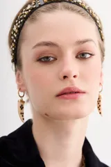 Aros colgantes compuestos por una argolla dorada pequeña y un dije de resina en forma de cuerno con incrustaciones de strass negro.