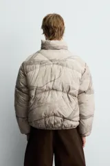 Cazadora acolchada de corte relajado confeccionada en tejido técnico con estampado abstracto de ramas. Presenta cuello subido, cierre frontal con cremallera, bolsillos laterales con cierre y puños y bajo elásticos.