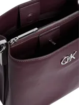 Cartera tipo saco Calvin Klein color borgoña, con correa larga regulable y logo CK plateado en el frente.