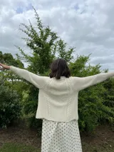Cardigan tejido a mano color crudo, con solapa en el escote y punto delicado.