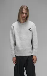 Sweater de cuello redondo color gris melange, con diseño de punto texturado y bordado en relieve con las letras 'Lx.' en el pecho. Presenta terminaciones en punto rib en cuello, puños y ruedo.