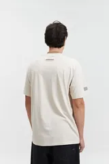 Remera de manga corta color beige, con escote redondo y fit regular. Presenta un estampado frontal en color marrón con la palabra "Resilience" en tipografía gótica y el texto "Original The World Has Changed Established Since 1976 // NLD Mistral".