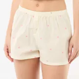 Pantalón corto de pijama de rayas amarillas con estampado de pequeñas flores rosadas, cintura elástica y botones decorativos frontales.