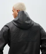 Chaqueta masculina de poliuretano color negro, con diseño de capucha, cierre frontal completo y puños elásticos. Presenta un acabado liso y estructura robusta.