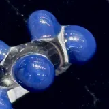 Anillo artesanal de vidrio transparente con diseño irregular y esferas de color azul intenso incrustadas.