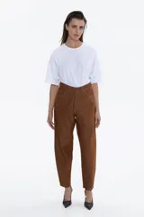 Pantalón de jean color marrón óxido, de tiro alto y calce relajado (slouchy) que se afina hacia el tobillo.