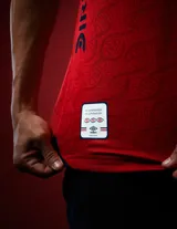 Camiseta de fútbol Umbro del Club Nacional de Football, modelo Away 2026. Diseño en color rojo con detalles en azul y blanco en el cuello y mangas. Incluye logo de Umbro, escudo del club y sponsors estampados en el frente y mangas.