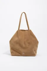 Bolso shopper grande de Bimba y Lola, confeccionado en serraje de piel vacuna con acabado de ante color marrón. Presenta doble asa de hombro y detalle de logo metálico de la marca en la parte inferior.