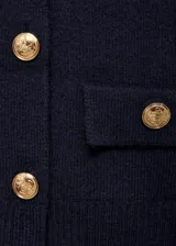 Chaqueta de punto de corte recto y estilo marinero, color azul marino. Presenta cuello polo, cierre frontal de doble botonadura con botones metálicos dorados y dos bolsillos de solapa delanteros. Posee mangas largas con terminaciones en canalé.