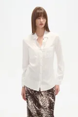 Camisa blanca de manga larga, corte al cuerpo, con cuello camisa y dos bolsillos frontales con tapa.