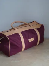 Bolso de lona color verde militar con detalles en cuero marrón. Tiene doble asa de mano y correa de hombro ajustable y extraíble.