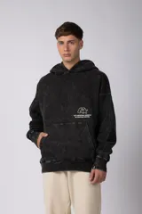 Buzo canguro oversize de algodón frizado con efecto gastado, capucha y bolsillo frontal tipo canguro. Presenta estampa gráfica sutil en el pecho.