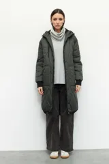 Campera de nylon larga oversized color negro, con capucha, tres bolsillos externos y uno interno. De tela capitoneada, con puños en las mangas y forro polar.