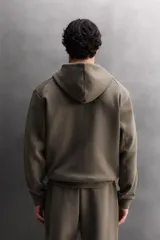 Sudadera con capucha de entrenamiento, confeccionada en tejido técnico de algodón con efecto neopreno. Presenta cierre frontal de cremallera, cuello subido, bolsillos laterales y un bolsillo en el pecho, todos con cierre de cremallera y acabado termofijado.