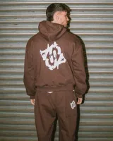 Conjunto de buzo canguro con capucha y pantalón de jogging color marrón, con diseño estampado en la espalda y el bolsillo trasero.