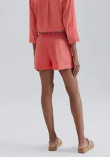 Short de lino en color crudo, de corte recto y tiro medio. Presenta una cintura con pasacintos y un cordón trenzado decorativo con borlas en el frente.