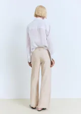 Pantalón de tiro medio color beige, de diseño recto y confeccionado en mezcla de algodón y lino. Cuenta con cuatro bolsillos, trabillas y cierre delantero con cremallera y botón.