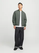 Campera bomber verde militar, liviana, de manga larga con cuello baseball y corte cómodo. Tiene cierre frontal de cremallera, bolsillos delanteros y puños de canalé.