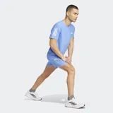 Short de running Adidas Own The Run, color azul claro, confeccionado en poliéster reciclado con tecnología AEROREADY. Presenta tres franjas blancas verticales en el lateral derecho y el logo de Adidas en la parte inferior izquierda.